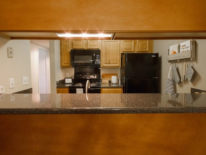 This image shows the breakfast bar featuring the trendy kitchen cabinets with granite-inspired countertops.
